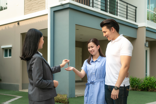Azji szczęśliwy uśmiech młoda para wziąć klucze nowy duży dom od agenta nieruchomości lub pośrednika nieruchomości przed ich domem po podpisaniu umowy, koncepcja nieruchomości, przeprowadzka do domu lub wynajem nieruchomości - Zdjęcie, obraz