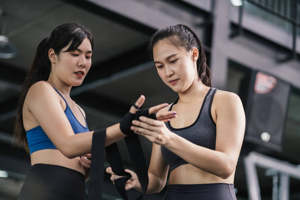 Sporty young asian women training boxer preparing strap on wrist with coach trainer, Boxing practice sports for fight or workout with a partner at fitness gym healthy lifestyle and self defending. - Φωτογραφία, εικόνα