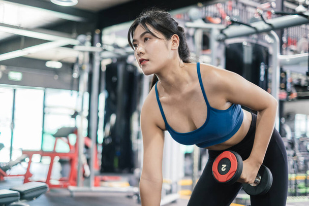 Sporty young asian women workout exercise dumbbell row pulling with dumbbell in the fitness gym, Sportive training healthy bodybuilding muscle, Athlete lifestyle concept. - Fotó, kép