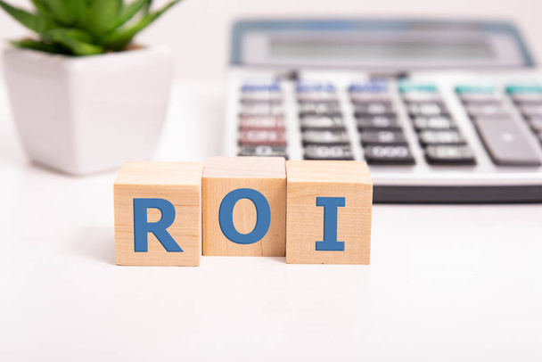 Return on Investment, ROI, performance measure of business or investment efficiency, target and goal, cube wooden block building the word ROI on chalkboard - 写真・画像