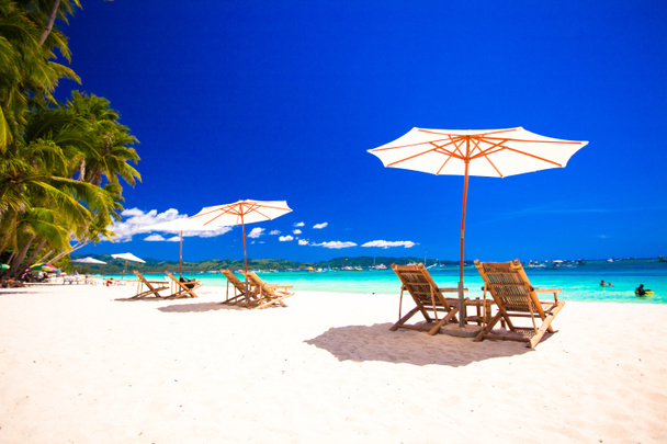 Парадоксальный вид на красивый пустой песчаный пляж с зонтиком и пляжным шезлонгом
 - Фото, изображение