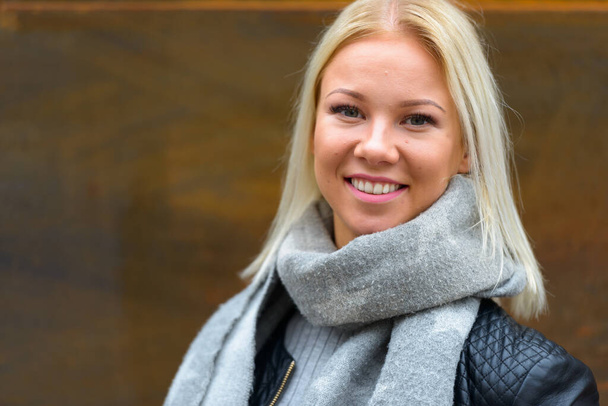 Porträt einer jungen schönen blonden Skandinavierin vor rostiger alter Metallwand im Freien - Foto, Bild