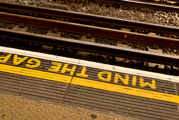 Поїзд платформи, намальований "Mind the Gap" попереджувальний знак. - Фото, зображення