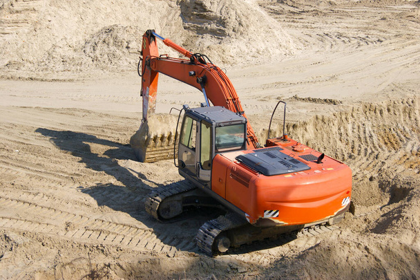 Orange excavator on a sand quarry. A lot of sand. - Photo, Image