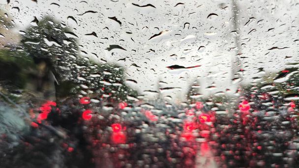 złapany w burzę. przednia szyba samochodu rozpryskuje się silną deszczową wodą od burzy. duże zatory komunikacyjne z czerwonymi tylnymi światłami ze wszystkich stron. problematyczna ulica Bangkoku - Zdjęcie, obraz