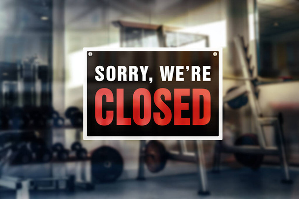 Image of closed sign in front of a blurred gym background. Closure or bankruptcy of gym or fitness center. - Photo, Image