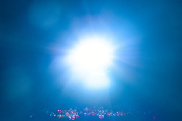 Niebieskie światło rozbłysk specjalny efekt i koraliki na czarnym tle, oświetlenie koncert . - Zdjęcie, obraz