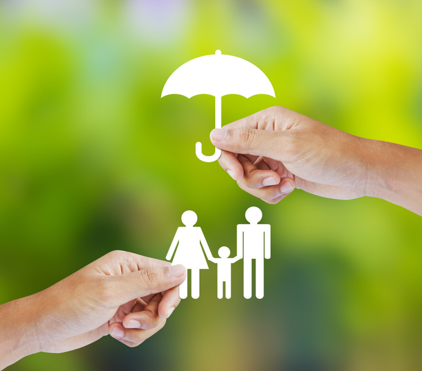 Mano sosteniendo una familia de papel y paraguas sobre fondo verde, concepto de seguro
 - Foto, Imagen