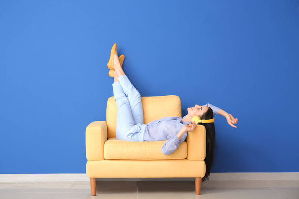 Young woman relaxing in armchair near color wall - Φωτογραφία, εικόνα