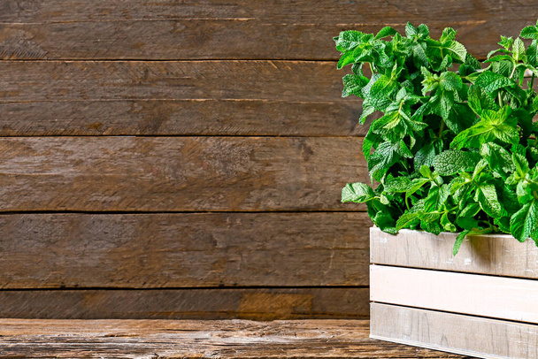 Fresh green mint in basket on wooden background - Photo, Image