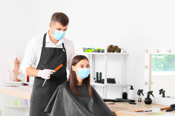 Muž kadeřník pracující s klientem v salonu během epidemie koronaviru - Fotografie, Obrázek