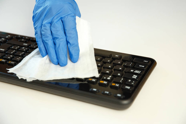 Office space wiping corona virus cleaning and disinfection of your workspace. Disinfecting wipes to wipe surface of keyboard, mouse at office. - Valokuva, kuva
