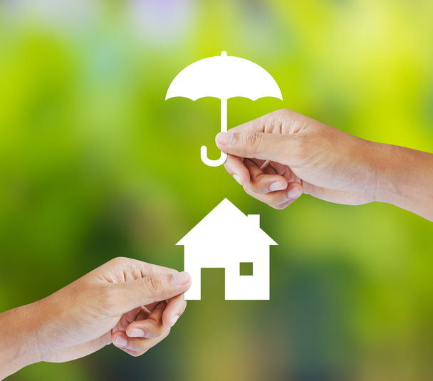 Main tenant une maison en papier et parapluie sur fond vert, concept d'assurance
 - Photo, image