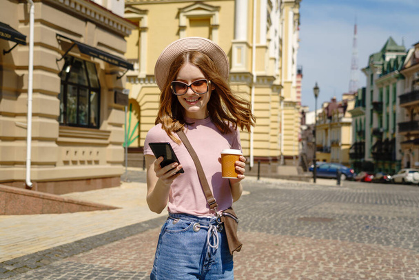 Beautiful Young Woman tourist with takeout coffee in the City Center talking on the phone - Фото, зображення