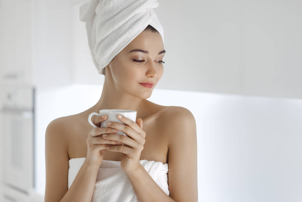 Mujer joven en toalla disfrutando del café en casa
. - Foto, Imagen