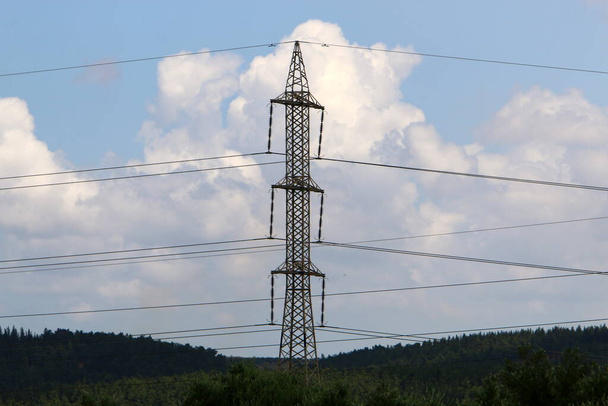 металлический опорный столб с изоляторами и электропроводами против голубого неба в Израиле  - Фото, изображение