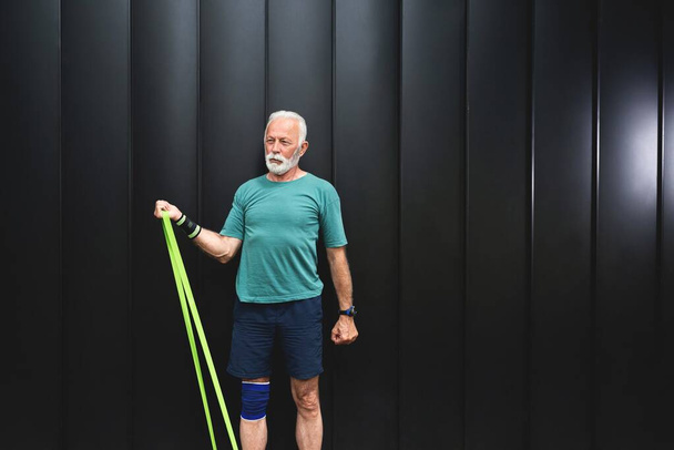 Senior sportsman exercising with resistance band, healthy lifestyle concept - Photo, Image