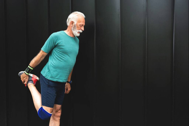 Старший спортсмен розтягує ноги для розігріву перед вправами, концепція здорового способу життя
 - Фото, зображення