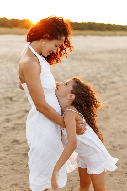 Mother hug daughter on the sea beach. Happy family in vacation and travel. Mom hug tender her daughter outside at the sea. - Photo, image