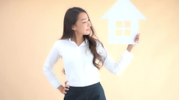 séquences de belle jeune femme d'affaires asiatique avec signe de maison isolé sur beige - Séquence, vidéo