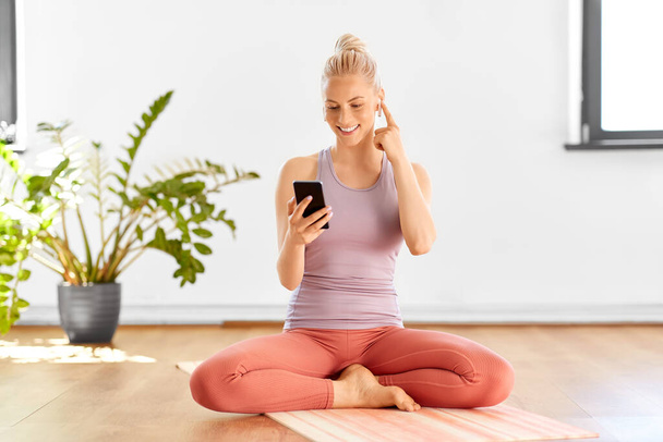 woman with phone and earphones doing yoga at home - Fotoğraf, Görsel