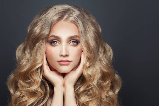 Piękna kobieta model włosów z długą zdrową blondynką kręcone fryzury na czarnym tle - Zdjęcie, obraz