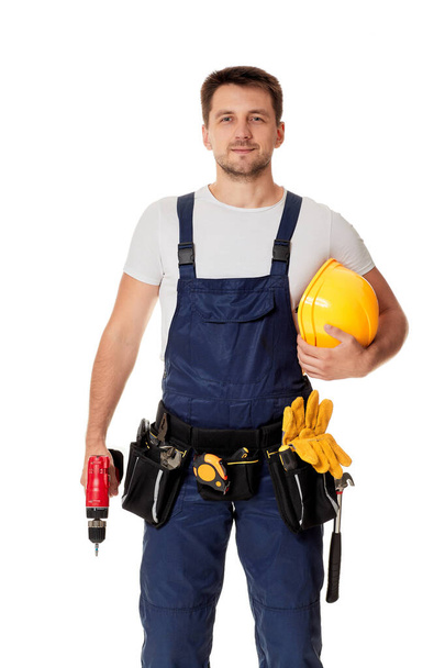 Jovem reparador caucasiano trabalhador com chapéu duro amarelo segurando chave de fenda sem fio
 - Foto, Imagem