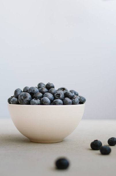 Fresh ripe blueberry in ivory bowl on blue background - Photo, Image