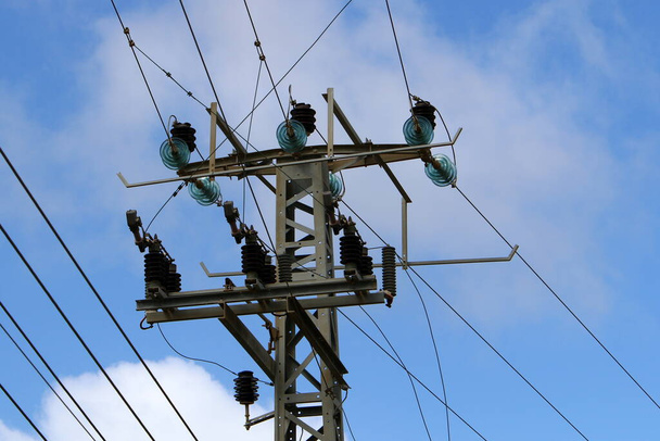İsrail 'de mavi gökyüzüne karşı yalıtkan ve elektrik kablolarıyla metal destek direği  - Fotoğraf, Görsel