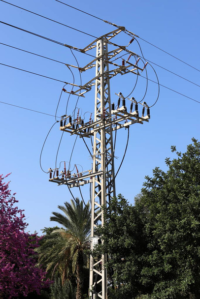 Metallstützstange mit Isolatoren und Elektrodrähten gegen den blauen Himmel in Israel  - Foto, Bild
