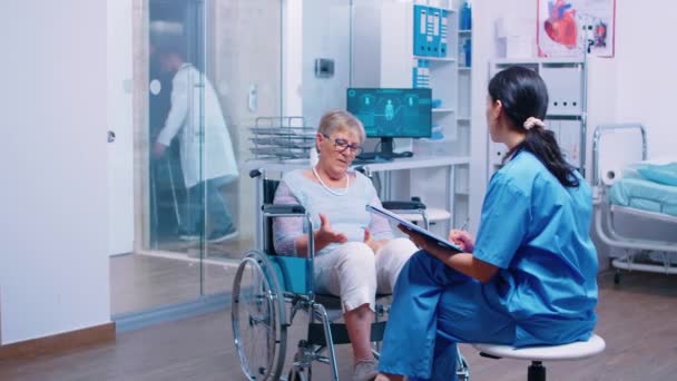 Νοσοκόμα μιλάει με ηλικιωμένη γυναίκα σε αναπηρική καρέκλα - Πλάνα, βίντεο