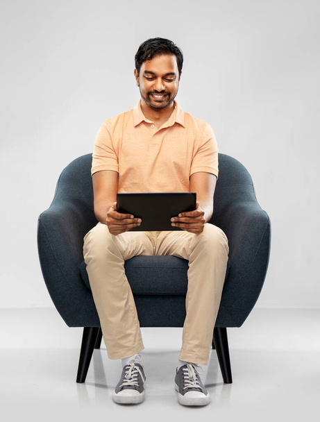 happy indian man with tablet pc computer in chair - Foto, imagen