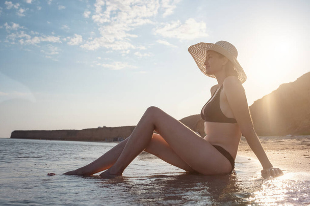 Bella giovane donna in spiaggia con il cappello. vacanze estive, vacanze, viaggi e concetto di persone - Foto, immagini