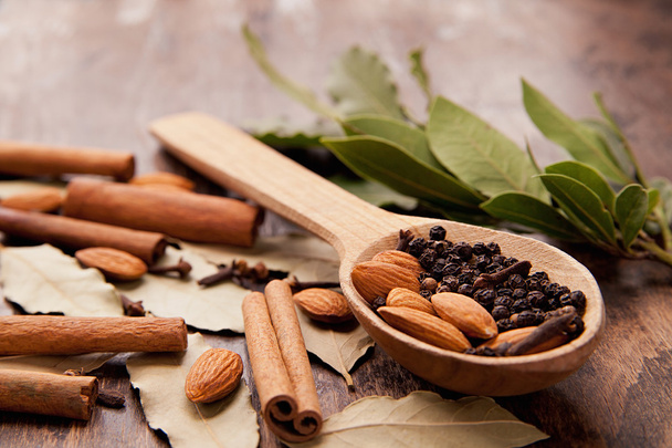 Pepper in wooden spoon with cinnamon, bay leaves - Fotografie, Obrázek