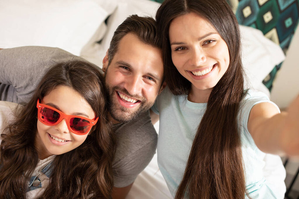 Beautiful young happy family making selfie photo in the bedroom and having fun together. - Φωτογραφία, εικόνα