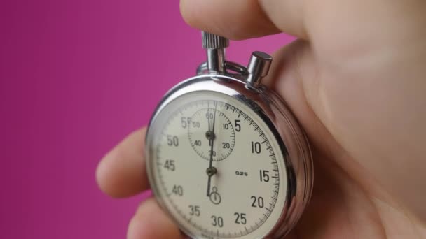 Cronometro analogico a mano maschile su sfondo rosa. Il tempo inizia con il vecchio cronometro uomo preme il pulsante di avvio nel concetto di sport. Concetto di gestione temporale. - Filmati, video