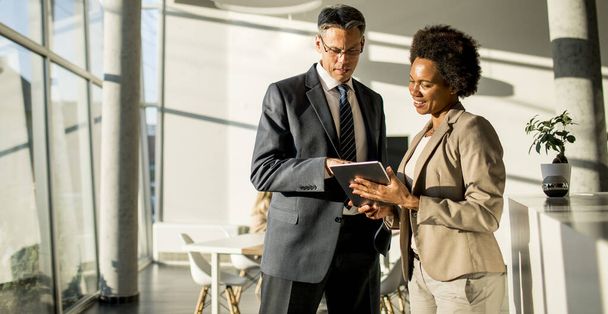 Багатонаціональні бізнесмени використовують цифровий планшет, стоячи в сучасному офісі
 - Фото, зображення