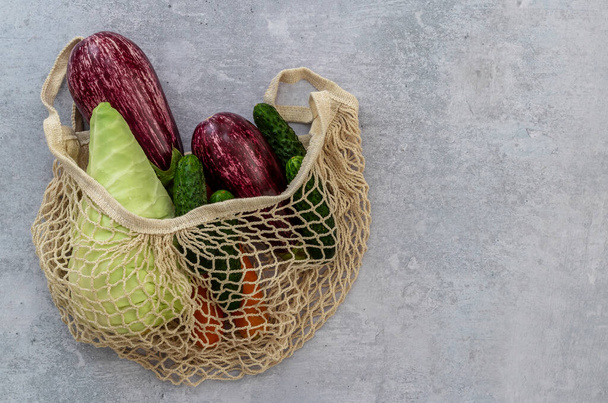Assortiment de légumes dans un sac à ficelle textile sur un fond clair. Chou, concombre, carotte, aubergine. La vue d'en haut. Pas de concept de magasinage plastique. - Photo, image