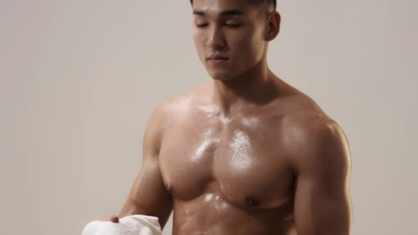 Tired Muscular Asian Man Indoors Against Gray Background - Video