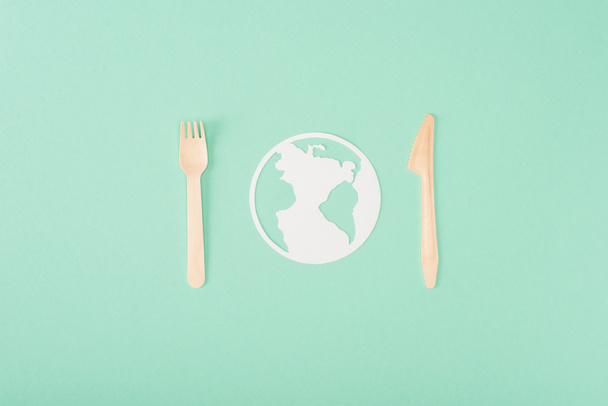 Top view of wooden cutlery and papers planet sign on green background, ecology concept - Photo, Image