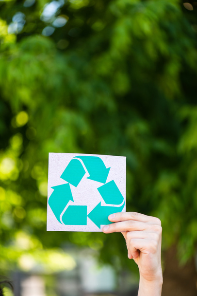 Gekropte weergave van de man die de kaart vasthoudt met recyclingbord buitenshuis, ecologisch concept - Foto, afbeelding