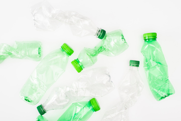 Vista dall'alto di bottiglie di plastica accartocciate su superficie bianca, concetto di ecologia - Foto, immagini