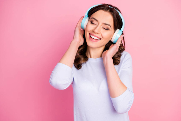 Closeup photo of beautiful lady wavy hairdo hold arms on cool modern technology headphones eyes closed enjoy youth music song wear casual white shirt isolated pink color background - Photo, image