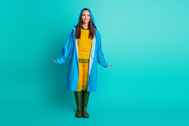 Full length photo of attractive lady beaming smile cheerful charming look rainy weather street walk wear casual outfit raincoat hood gumboots isolated teal color background - Valokuva, kuva