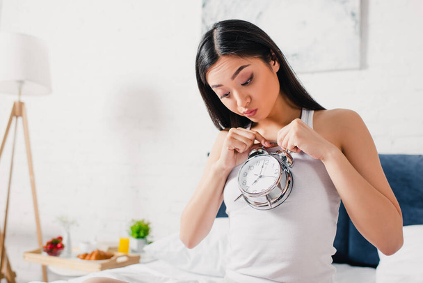 Surpreendido asiático mulher olhando para despertador relógio no quarto de manhã
  - Foto, Imagem
