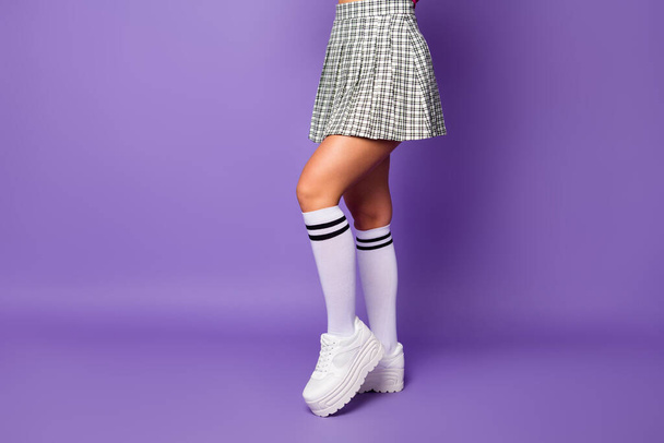 Cropped profile photo of lady showing cool stylish clothes outfit fit slim legs wear short plaid skirt long knee socks white shoes isolated pastel purple color background - Zdjęcie, obraz