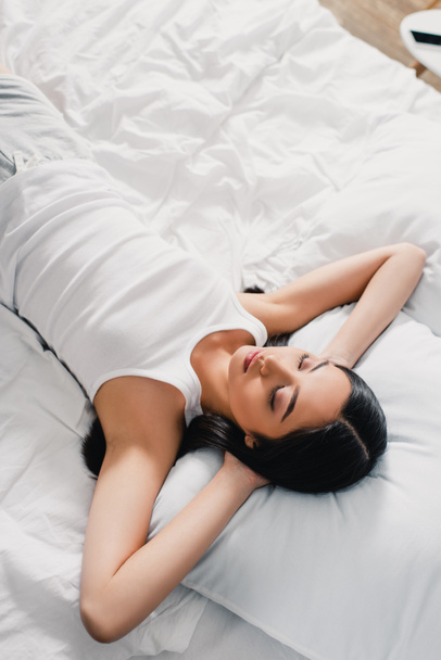 High angle view of young asian woman in sleeveless shirt sleeping on bed at morning  - Foto, immagini