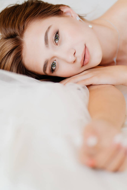 chica con maquillaje natural, la piel brillante se encuentra en la cama - Foto, Imagen