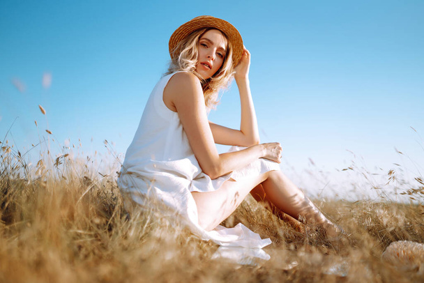 Junge Frau in weißem Leinenkleid und Hut mit einem Spiegel in der Natur. Sommer, Schönheit, Mode, Glamour, Lifestylekonzept. - Foto, Bild