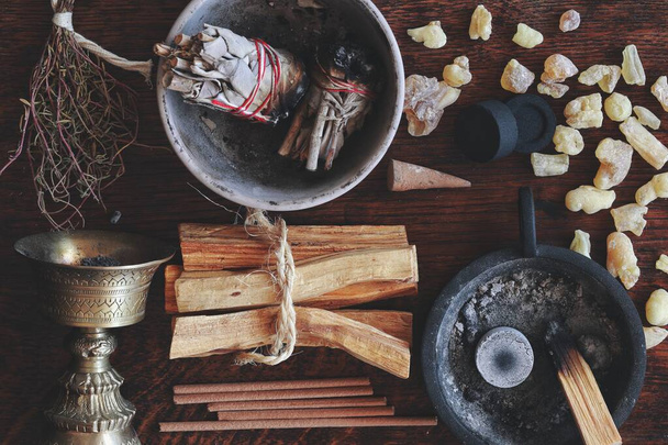 Flat lay various kinds of air element objects to use in witchcraft and wicca on witch's altar filled with sage smudge sticks, incense, Palo Santo tree, frankincense, charcoal disks for smoke cleansing - Photo, Image
